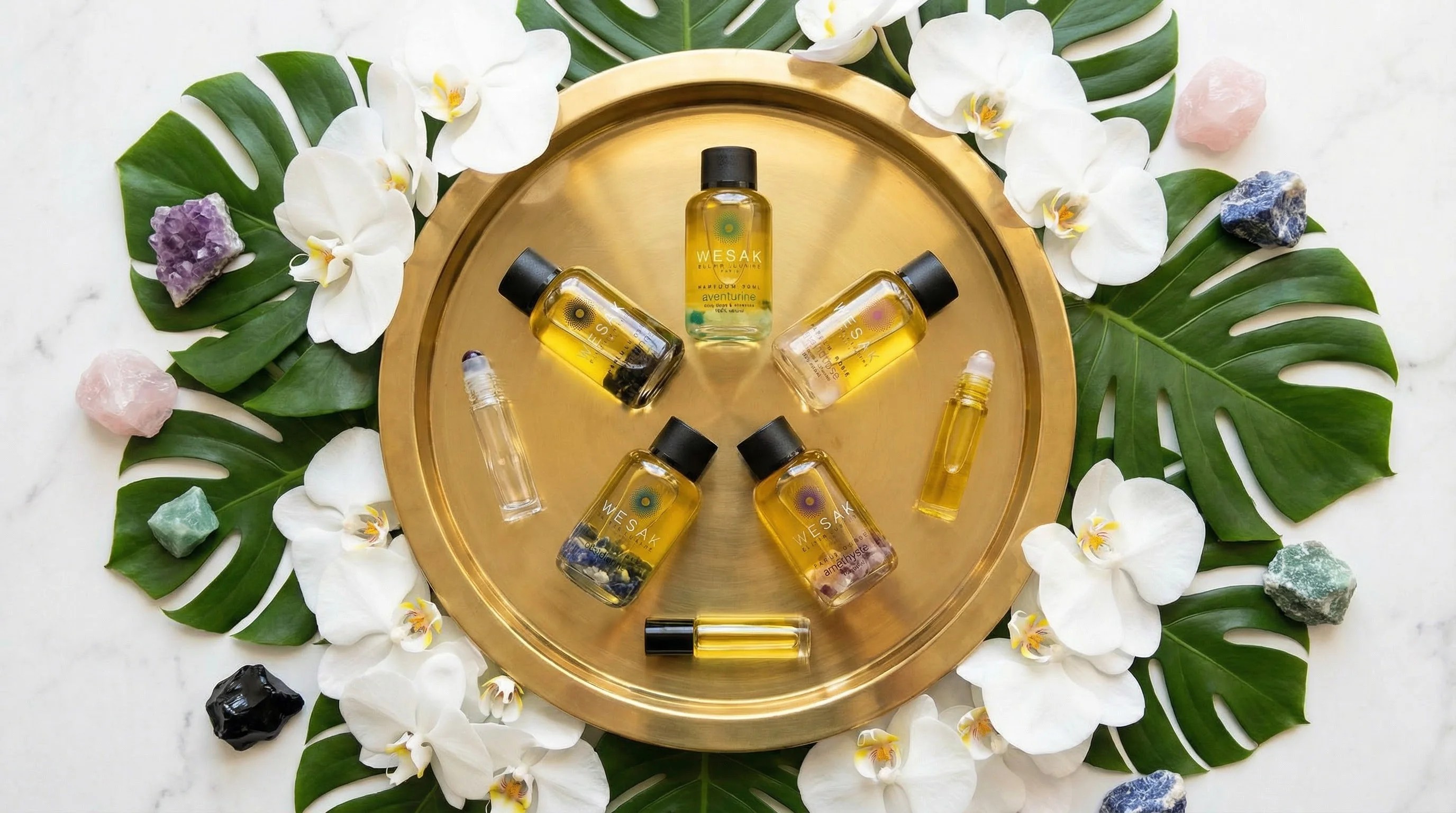 Les 5 recharges d'élixirs Wesak Paris (Améthyste, Aventurine, Obsidienne, Quartz Rose, Sodalite) dans une composition circulaire luxueuse avec orchidées et éléments naturels - cosmétique rechargeable zéro déchet
